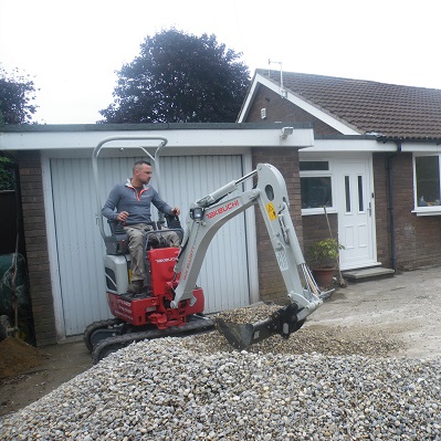 Takeuchi TB210R micro excavator working on a residential driveway project